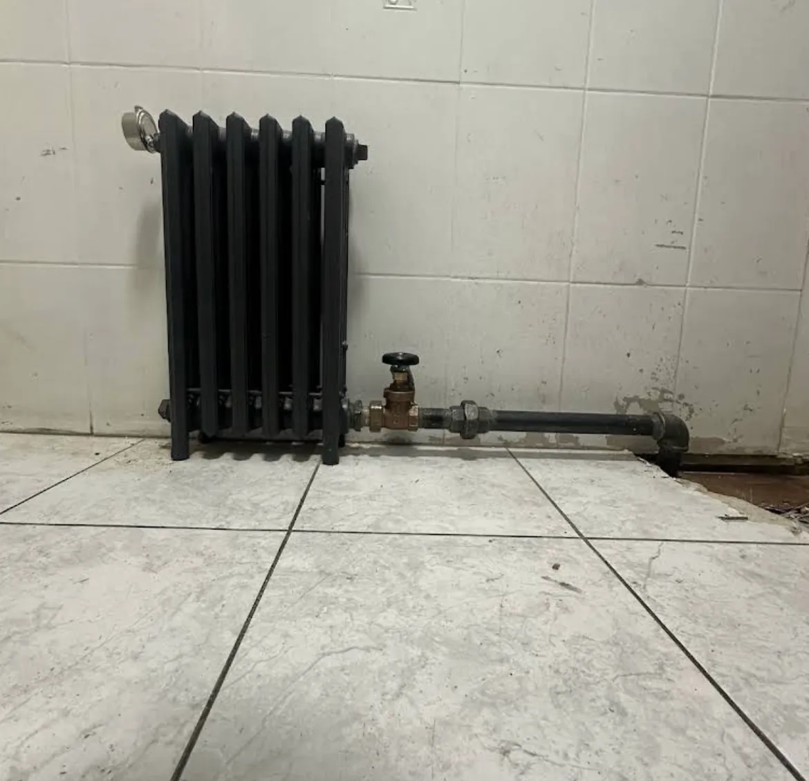 Cast iron radiator with its shutoff valve and copper supply pipe