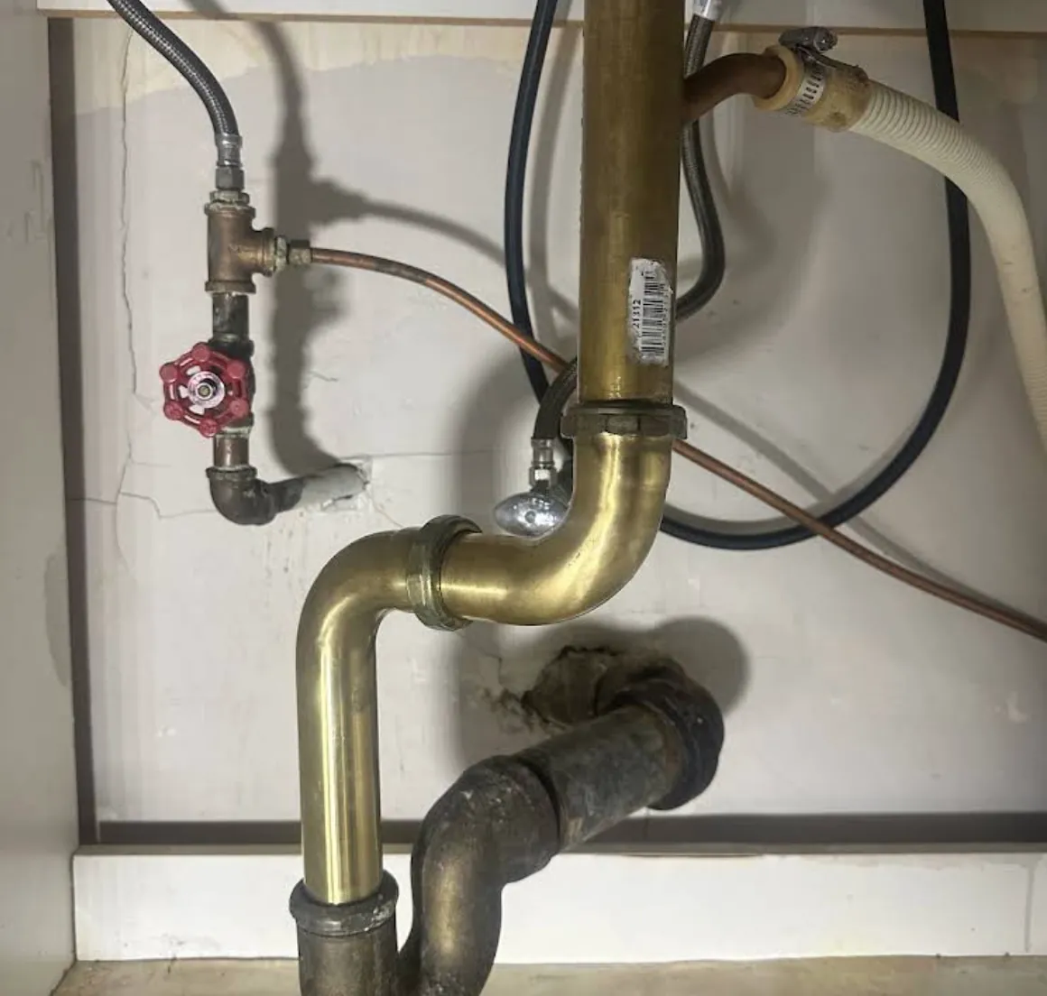 Brass drain trap and shutoff valve under a sink