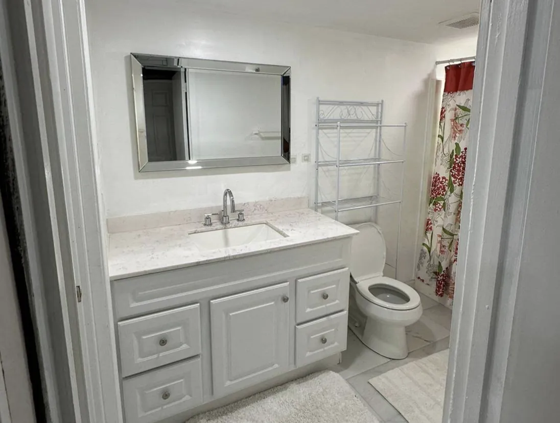 Bathroom vanity with gray cabinet, stone top, mirror and faucet